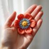 Hand holding a handmade crochet flower with delicate yarn petals.